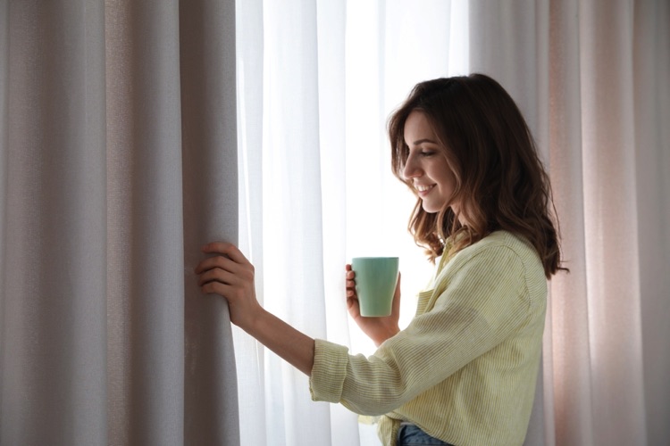 Woman drinking tea admiring her curtains
